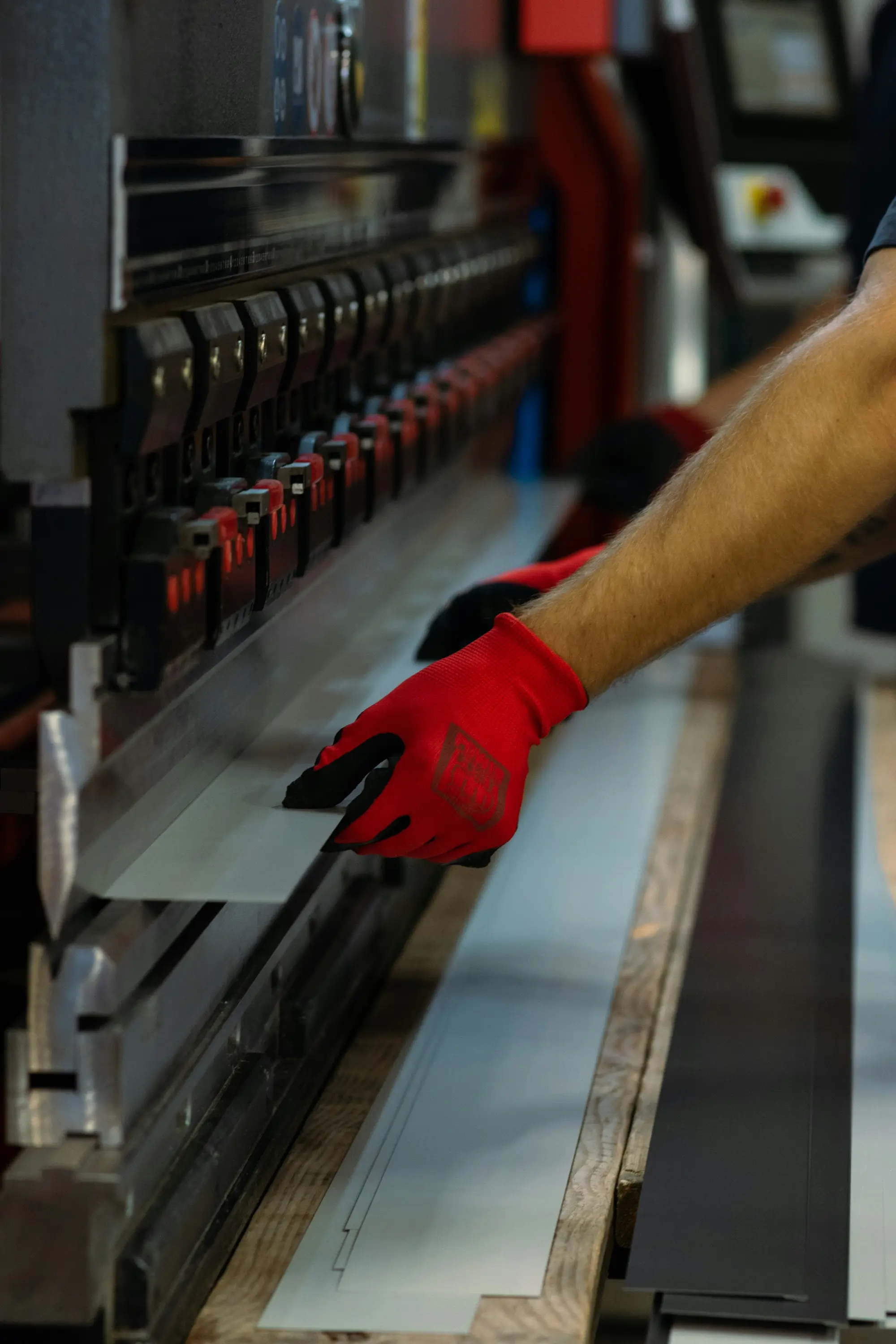 Worker operating an industrial press brake to bend a sheet of metal.